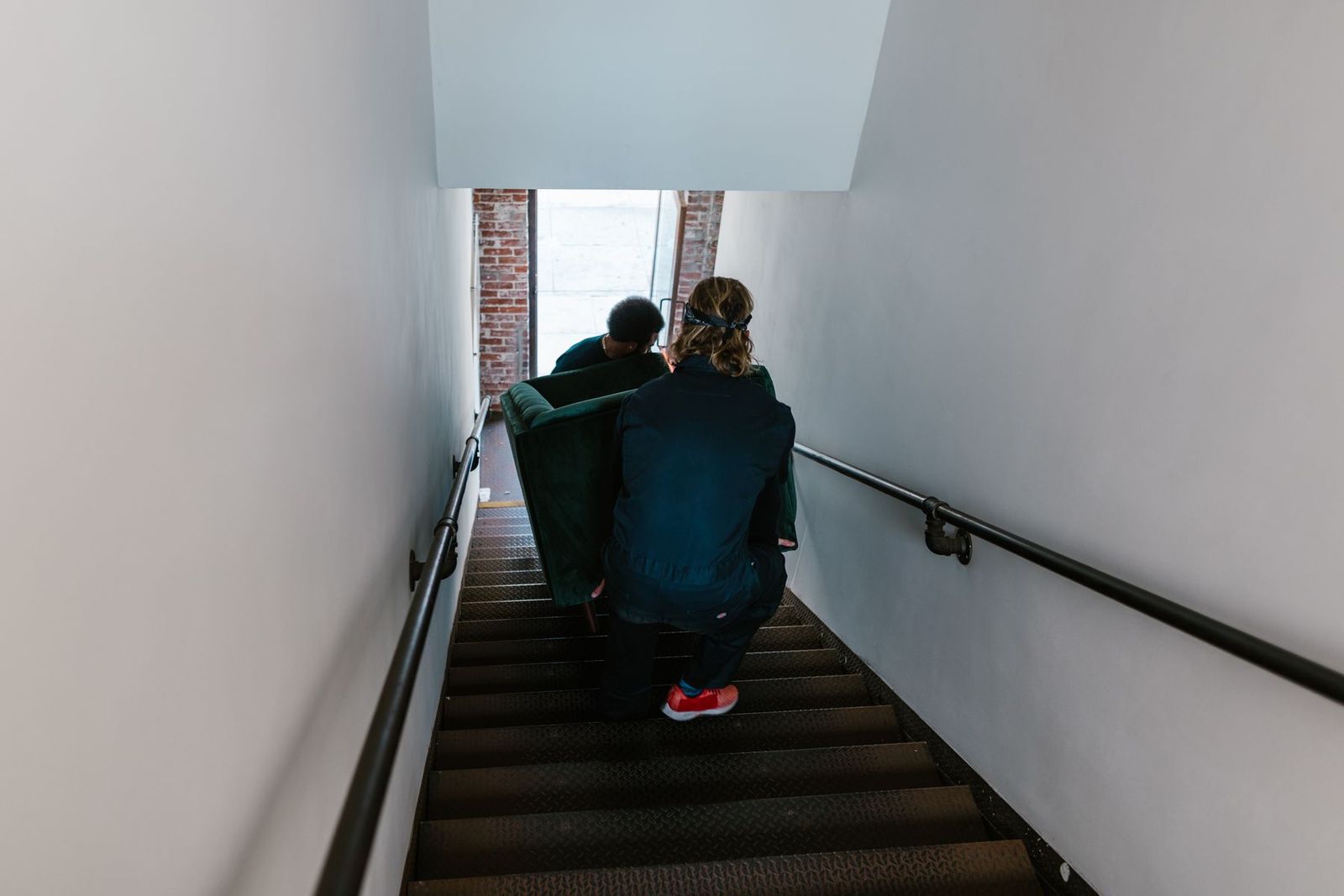 Zwei Umzugshelfer tragen ein Sofa vorsichtig die Treppe hinunter